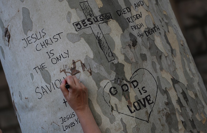 A mourner writes a tribute to victims on a tree near the scene of the attack