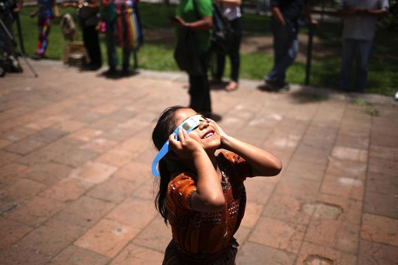 A girl uses protective glasses to view the eclipse from the atrium of the Church of La Mercen in Antigua, Guatemala