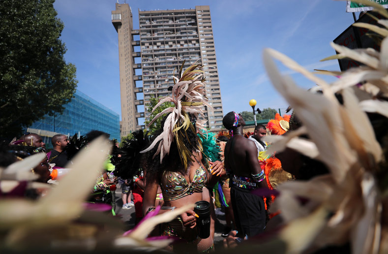 Masqueraders dance in the streets near Trellick Tower as they take part in Notting Hill Carnival.