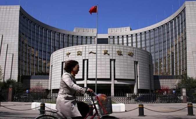 A woman rides past the headquarters of the People's Bank of China in Beijing, April 3, 2014