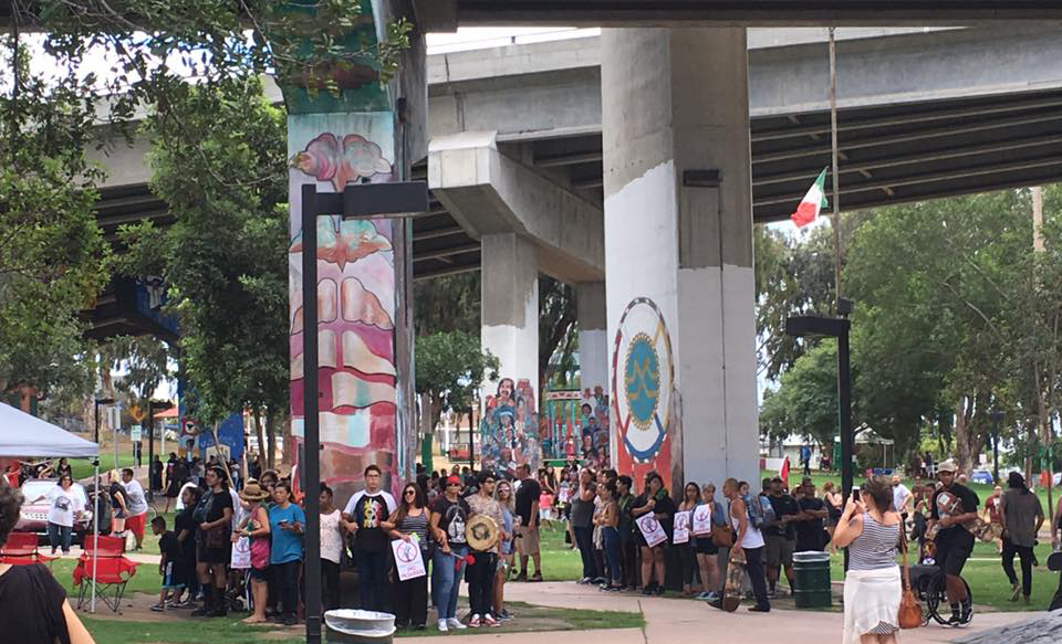 Members of San Diego's Barrio Logan community surround mural-covered pylons threatened by ultra-right groups.