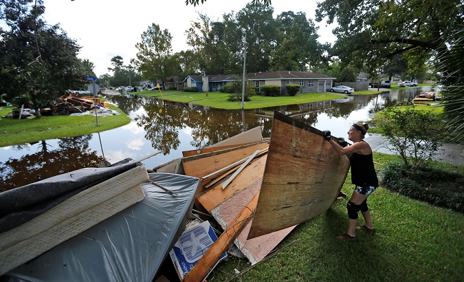 A woman piles debris outside of her home that was flooded by Tropical Storm Harvey in Orange, Texas.
