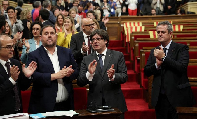 Catalonia's President Carles Puigdemont stands with deputies after voting for an Oct. 1 independence referendum in the Catalan Parliament in Barcelona, Sept. 6, 2017.