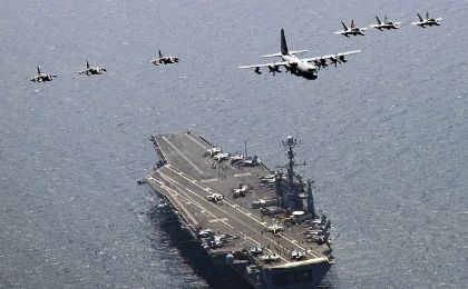 A U.S. Marine Corps C-130 Hercules aircraft leads a formation over the aircraft carrier USS George Washington in the East Sea of Korea.