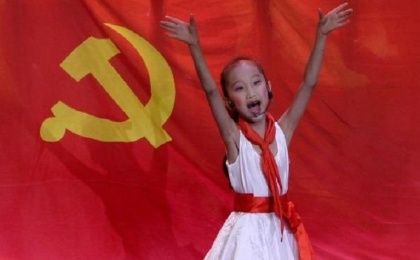 A schoolgirl performs in front of the flag of China's Communist party.