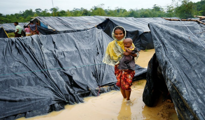 A Rohingya refugee woman and her child walk in floodwaters near makeshift shelters after heavy rains in Cox's Bazar, Bangladesh. 