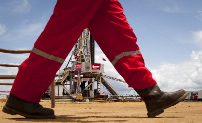 An oil worker walks past a drilling rig at an oil well operated by Venezuela's state oil company PDVSA in Morichal July 28, 2011.