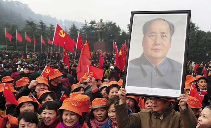 A man holds up a portrait of the late Chinese revolutionary leader, Chairman Mao Zedong.