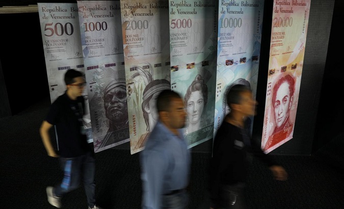 People walk by banners of Venezuelan bolivar notes displayed at the Venezuelan Central Bank building in Caracas, Venezuela.