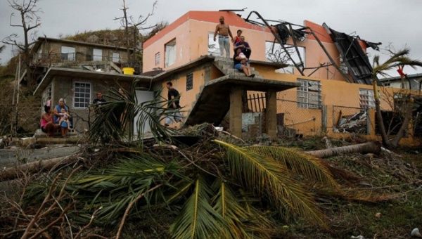 People rest outside a damaged house after the area was hit by Hurricane Maria in Yabucoa, Puerto Rico.