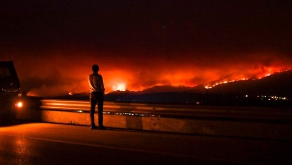 A man stands on the roadside watching a wildfire at Anciao, Leiria, central Portugal.
