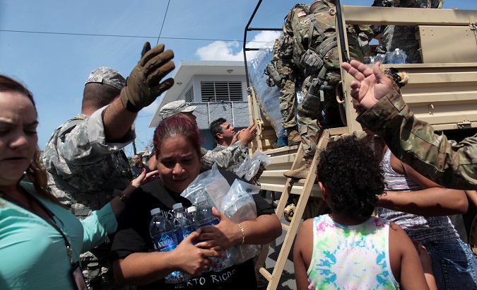 A woman carries bottles of water and food during a distribution of relief items, after the area was hit by Hurricane Maria in San Juan.