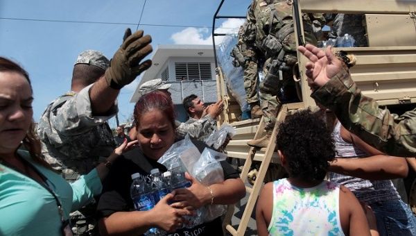 A woman carries bottles of water and food during a distribution of relief items, after the area was hit by Hurricane Maria in San Juan.