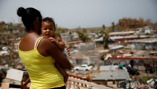Ysamar Figueroa carrying her son Saniel, looks at the damage in the neighbourhood after the area was hit by Hurricane Maria, Sept. 26, 2017. 