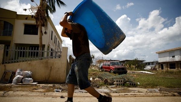 A man carries a container filled with water after the area was hit by Hurricane Maria in Toa Baja, Puerto Rico