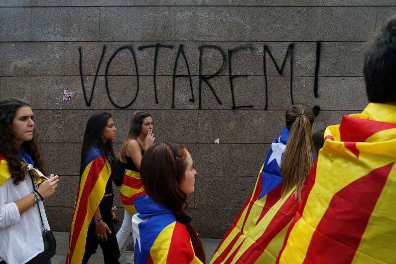 Students wear Esteladas (Catalan flag) during a demonstration. The graffiti on the wall reads, 