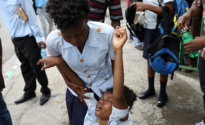 A girl holds a friend affected by tear gas after Haitian National Police officers fired it to disperse a demonstration against the government in Port-au-Prince.