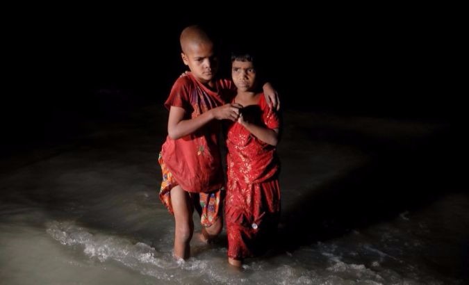 Rohingya refugee sisters, who just arrived under the cover of darkness by wooden boats from Myanmar, hug each other as they try to find their parents at Shah Porir Dwip, in Teknaf, near Cox's Bazar in Bangladesh.