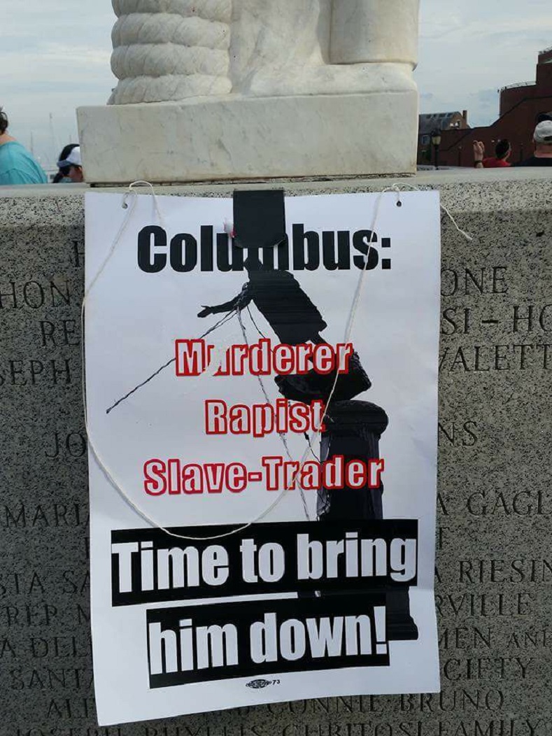A protest banner draped over a statue in Boston, Massachusetts calls Christopher Columbus a 