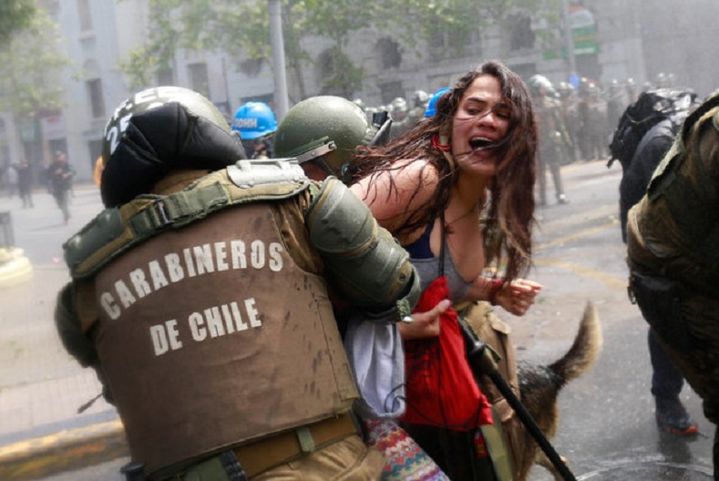A demonstrator is detained by riot police during a rally against Columbus Day in downtown Santiago.