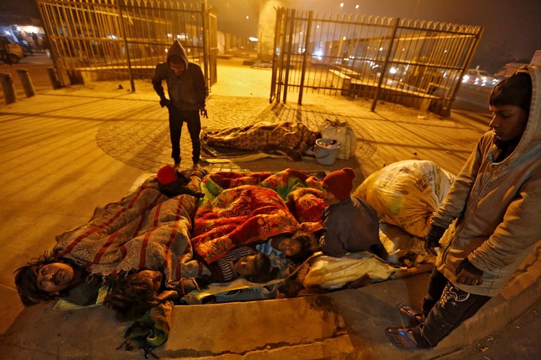A family gathers under blankets to shelter from the cold beneath a flyover in Delhi, India.
