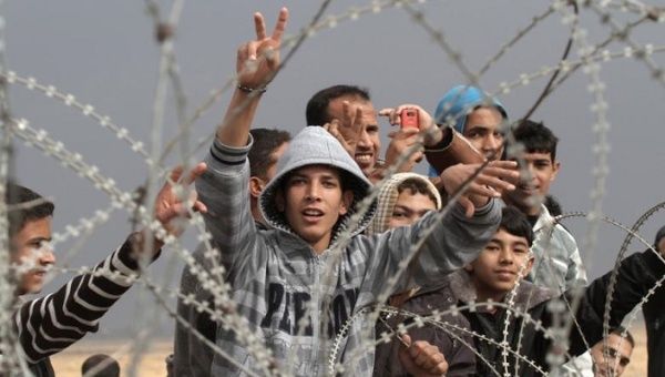 Palestinian youths gesture during a demonstration next to the security fence standing on the Gaza border.