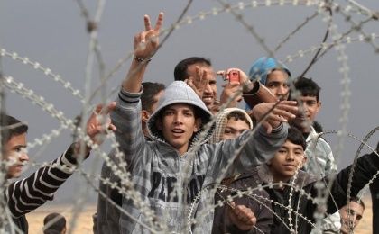 Palestinian youths gesture during a demonstration next to the security fence standing on the Gaza border.