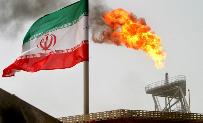 A gas flare on a production platform in the Soroush oil fields, alongside an Iranian flag in the Gulf.
