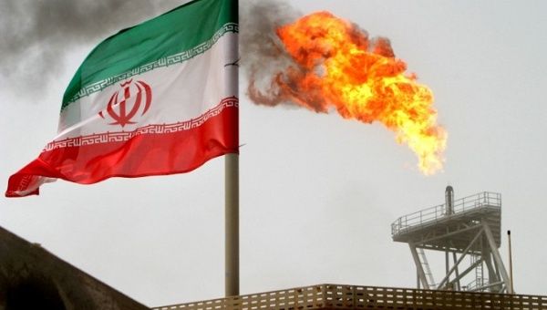 A gas flare on a production platform in the Soroush oil fields, alongside an Iranian flag in the Gulf.