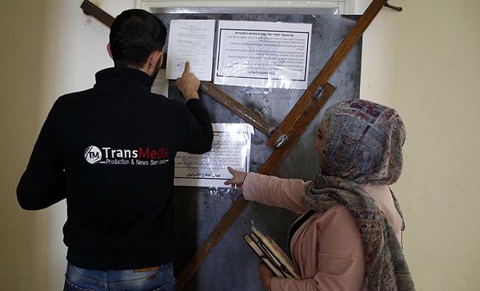 Employees of TransMedia look at a military order attached to their office doors in Hebron on October 18, 2017.