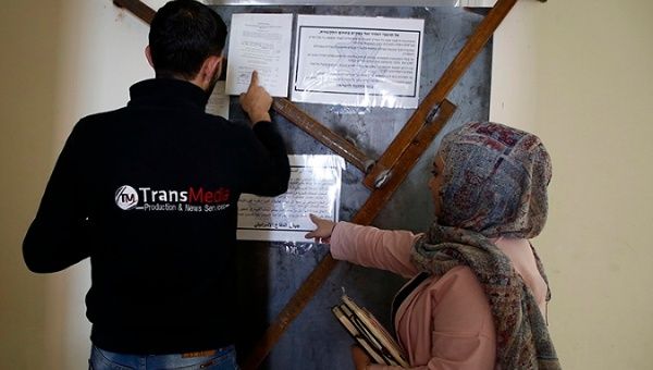 Employees of TransMedia look at a military order attached to their office doors in Hebron on October 18, 2017.