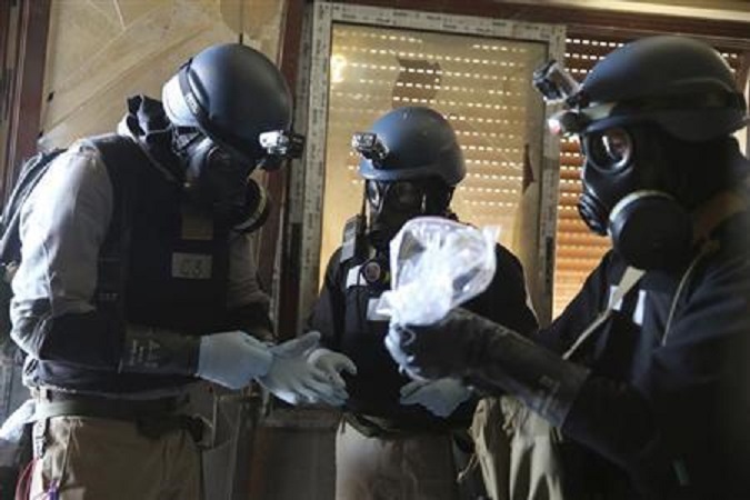 A U.N. chemical weapons expert, wearing a gas mask, holds a plastic bag containing samples from one of the sites of an alleged chemical weapons attack in the Ain Tarma neighbourhood of Damascus August 29, 2013.