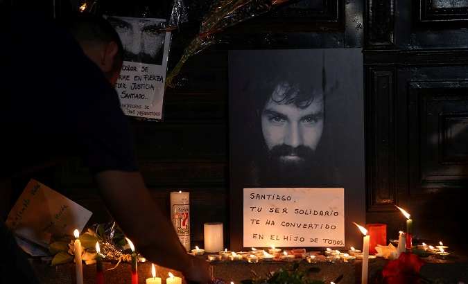 A man lights candles next to a portrait of Santiago Maldonado at the entrance of a judicial morgue in Buenos Aires, Argentina, October 20, 2017