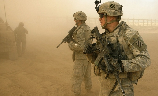 U.S. soldiers walk in a cloud of dust as a Blackhawk helicopter takes off.