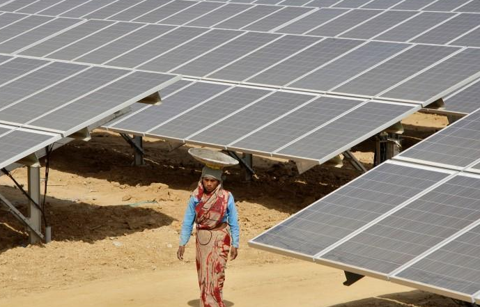 A worker walks through the installed solar modules at the Naini solar power plant in Allahabad