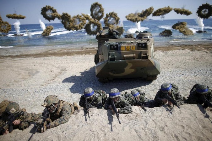 South Korean (blue headbands) and U.S. Marines take positions as amphibious assault vehicles of the South Korean Marine Corps fire smoke bombs during a joint landing operation drill in Pohang, South Korea, March 12, 2016.