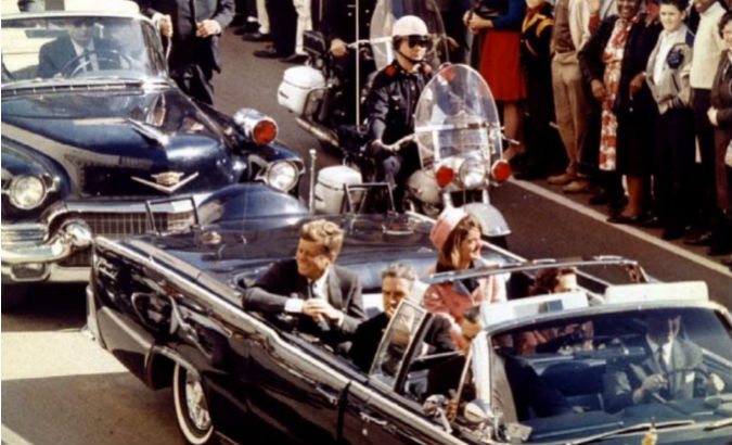 President John F. Kennedy and first lady Jacqueline Kennedy ride in the back seat of an open convertible moments before Kennedy was assassinated.