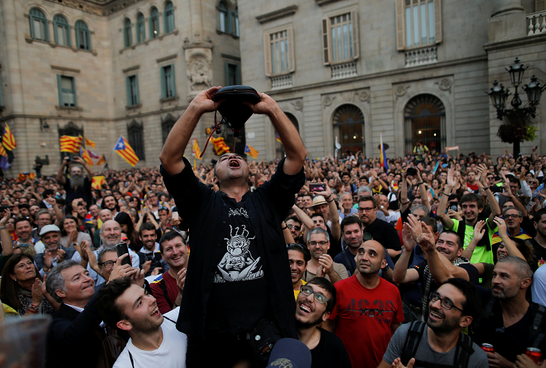 A man drinks from a wineskin as people gather in front of the Catalan regional government headquarters after the regional parliament declared independence from Spain in Barcelona.