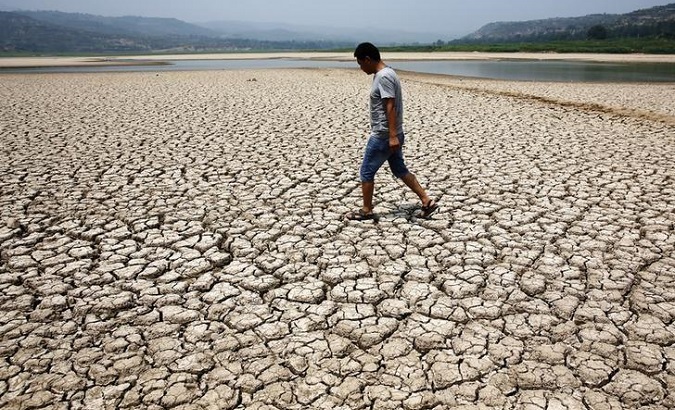 A man walks across the dried-up bed of a reservoir in Sanyuan county in China's Shaanxi province, July 30, 2014.