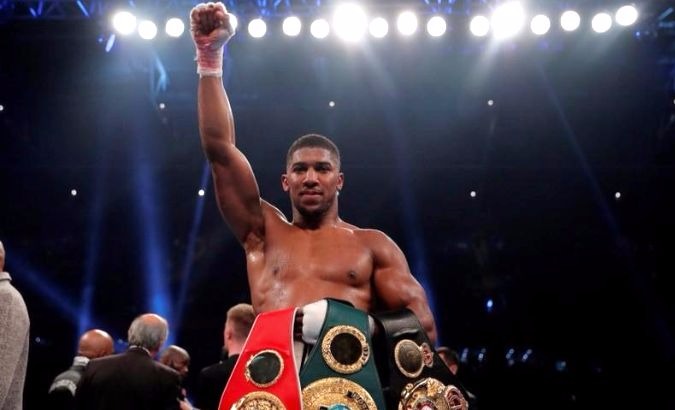 Briton Anthony Joshua displays his three belts during his celebration of his win over challenger Carlos Takam.