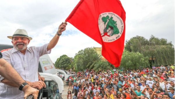 Lula holds up a Landless Worker's Movement flag during his sojourn through Minas Gerais state.