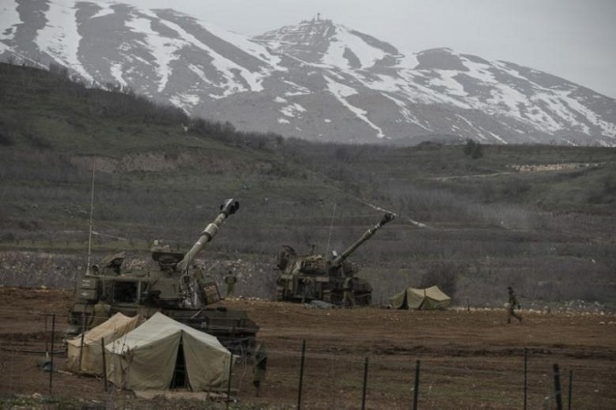 Israeli soldiers walk near mobile artillery units near the border with Syria in the Golan Heights January 27, 2015.