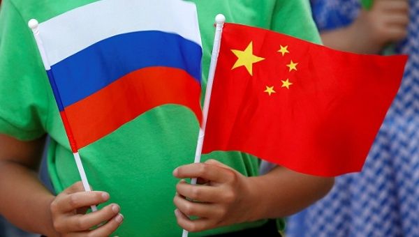 A child holds the national flags of Russia and China prior to a welcoming ceremony.