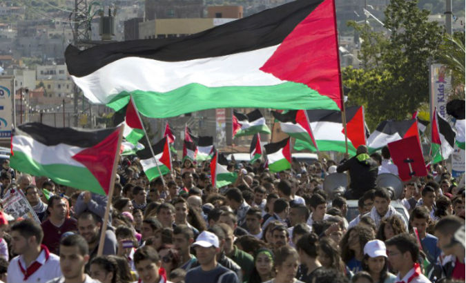Palestinians march and wave their national flag.