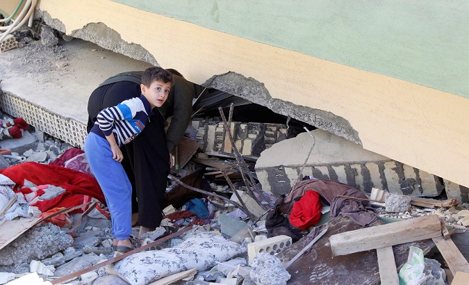 A man and child look at a damaged building following the 7.3 magnitude earthquake in the town of Darbandikhan, Iraq.