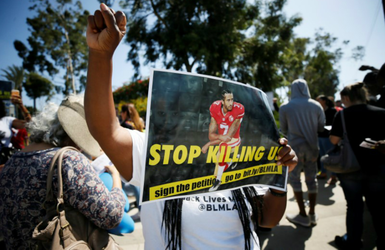 A protester demonstrates and holds a sign with Colin Kaepernick on it in support of NFL players who 