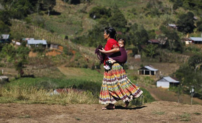A Guatemalan Indigenous woman carries a child on her back in the village of Pumbach, 130 miles from Guatemala city