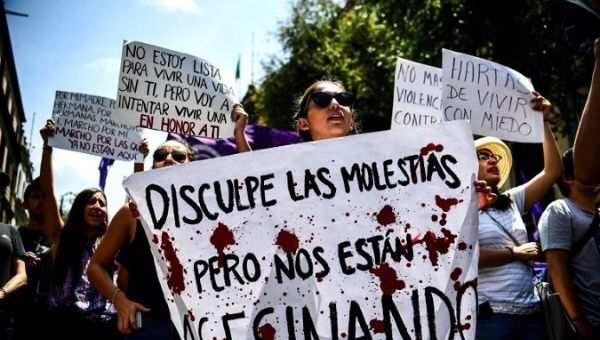 A Mexican woman holds a sign reading: 