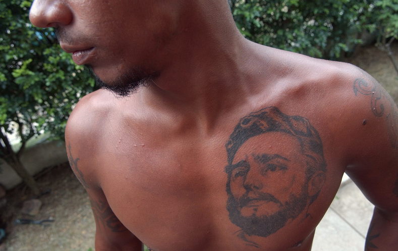 A young Cuban man showing off a tattoo of Fidel over his heart.