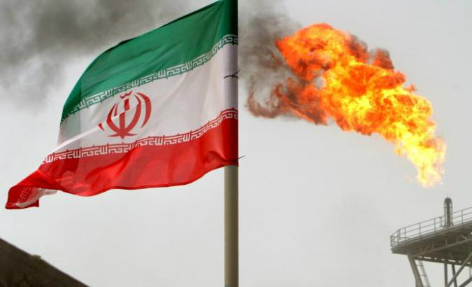 A gas flare on an oil production platform is seen alongside an Iranian flag in the Gulf July 25, 2005.